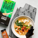 Miso broth pouring into a ramen bowl with vegetables
